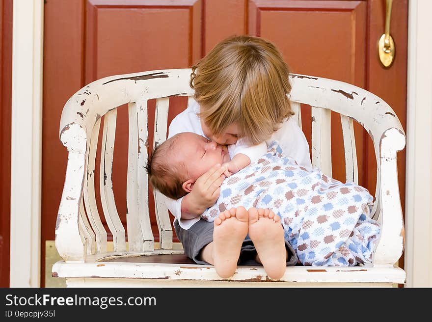 Portrait of young boy sat outside home cuddling newborn baby brother. Portrait of young boy sat outside home cuddling newborn baby brother.