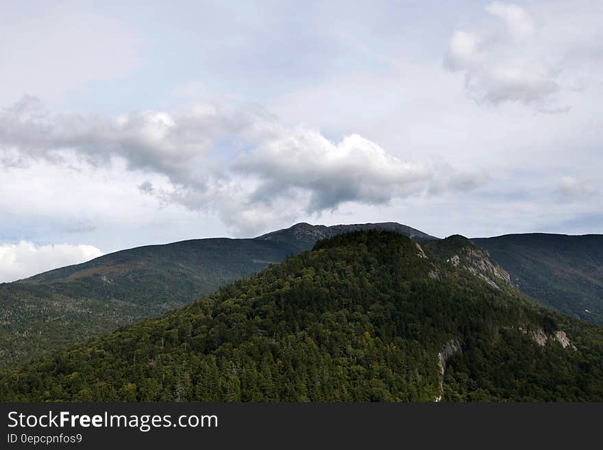 Scenic view of forest covered mountain landscape with cloudscape background.