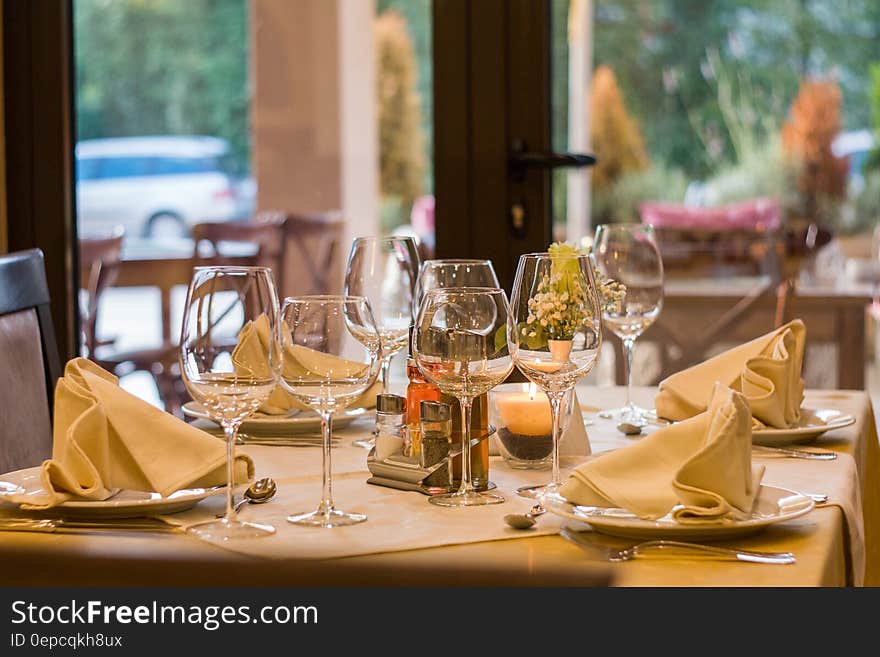 Empty restaurant table set with fine china and glassware on sunny day.