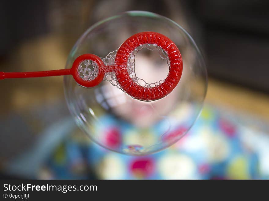 Close up of soap bubble on red wand.