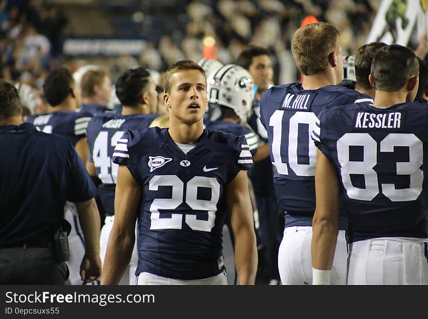 Young football players in uniform on sideline of field during night game. Young football players in uniform on sideline of field during night game.