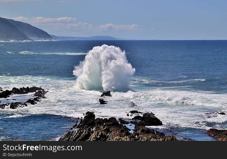 Waves breaking along rocky shores on sunny day with blue skies. Waves breaking along rocky shores on sunny day with blue skies.