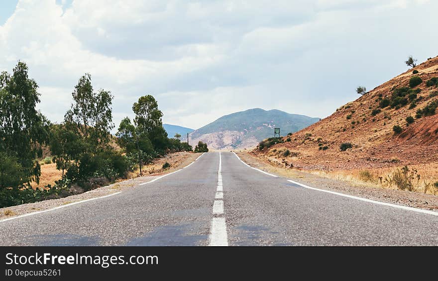 Empty road through desert with hills on sunny day.