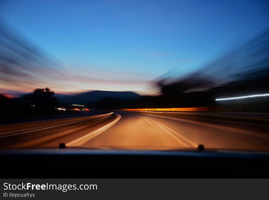 Blur of car driving on empty roadway at sunset. Blur of car driving on empty roadway at sunset.