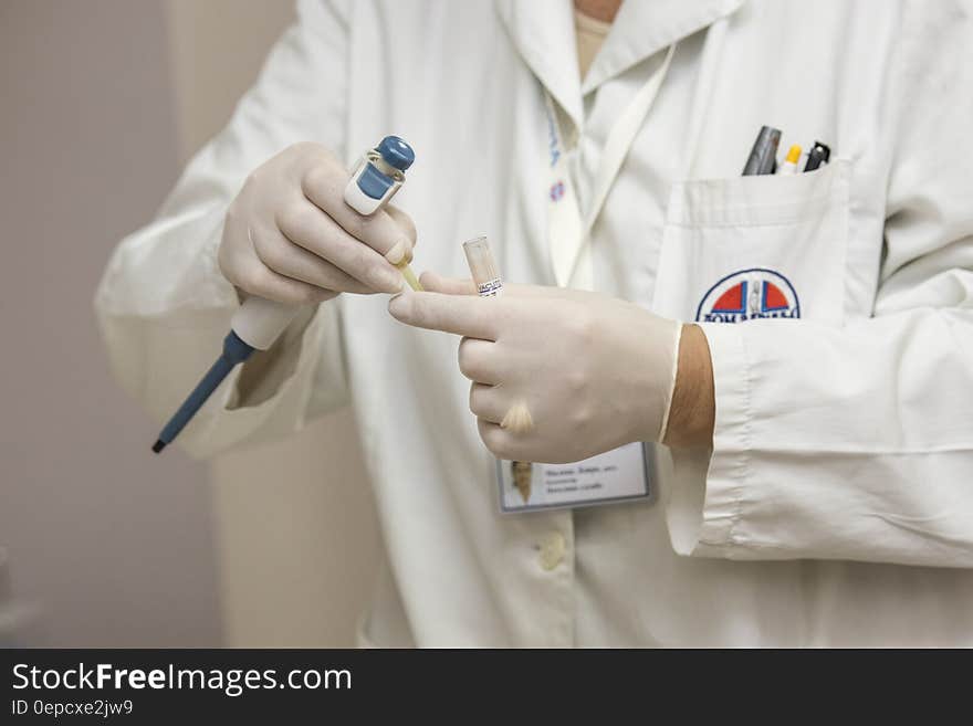 Clinician in white lab coat and gloves holding laboratory equipment. Clinician in white lab coat and gloves holding laboratory equipment.