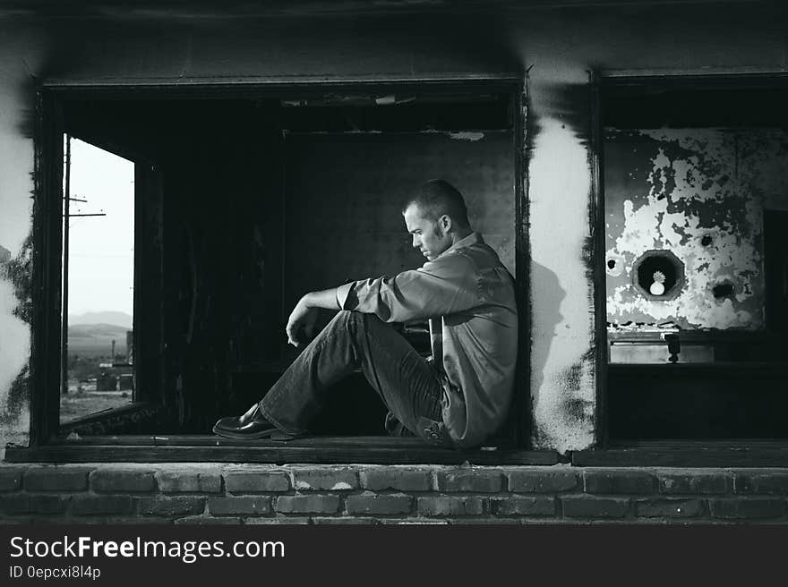 Man sitting outdoors in urban decay in black and white. Man sitting outdoors in urban decay in black and white.