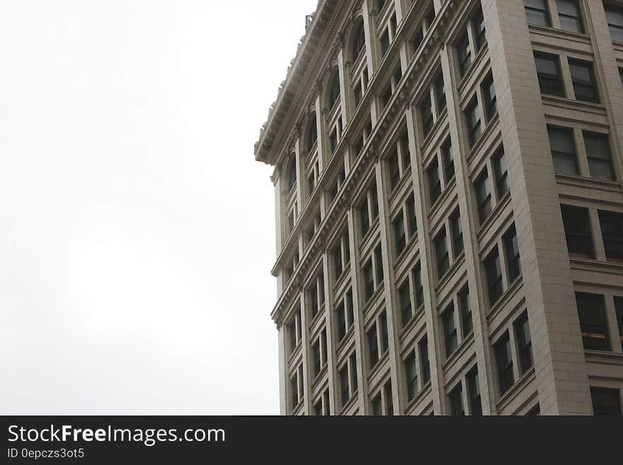 Gray high rise apartment block with repetition of pairs of windows on each floor and limited amount of decoration but providing empty space alongside a background on architectural subjects.