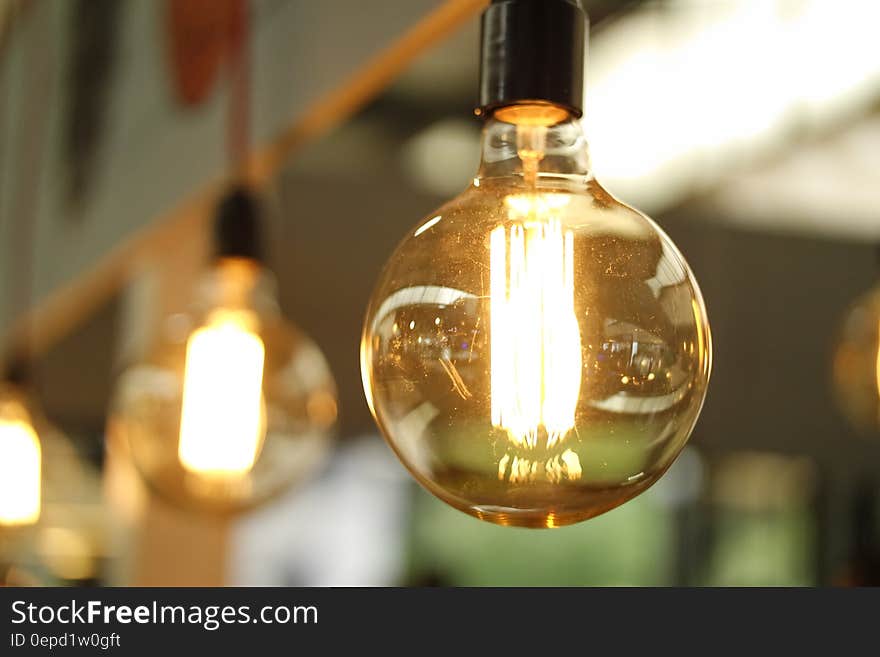 Close up of clear light bulb handing in fixture from ceiling indoors.