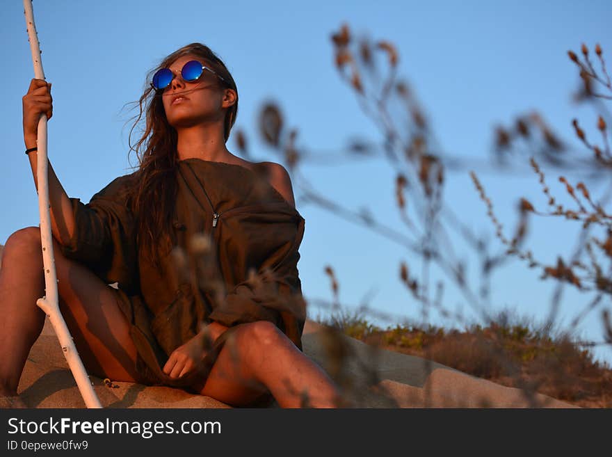 Woman in Brown Shirt Sitting Near Green Plant Under Clear Blue Sky