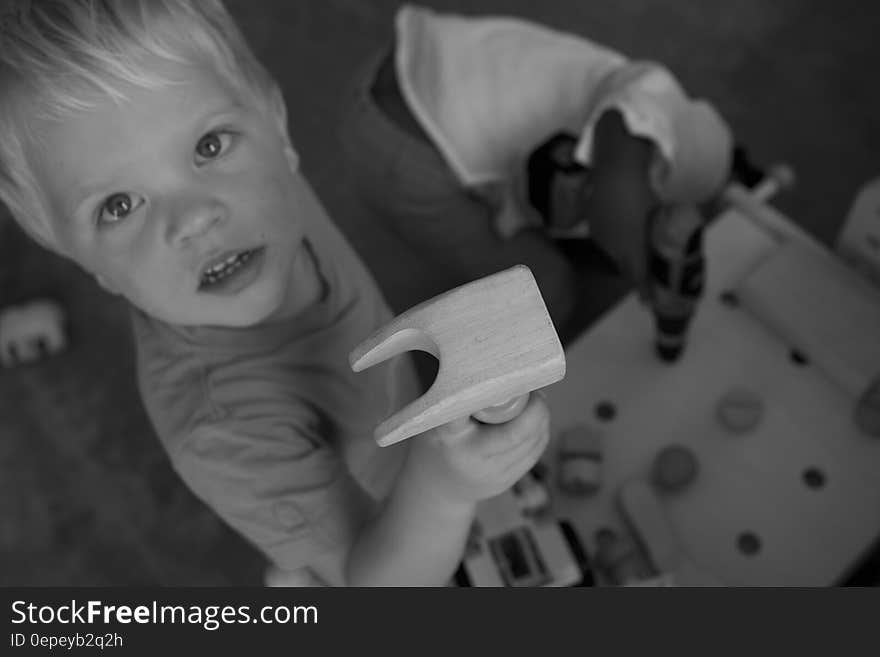 Greyscale Photo of Boy on Tshirt Holding Brown Wood