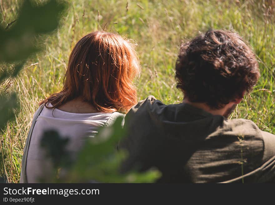 People Photography of Man and Woman Sitting on Green Grass Field