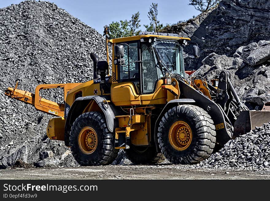 Orange and Black Tractor Next to Piles of Rocks