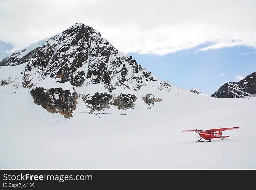 Red biplane in snow covered alpine field on sunny day. Red biplane in snow covered alpine field on sunny day.