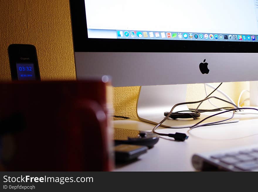 Silver Imac Turned on Beside Red Ceramic Cup