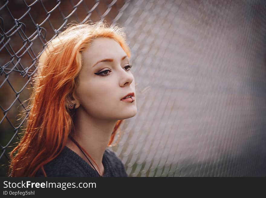 Woman Leaning on Gray Chain Link Fence