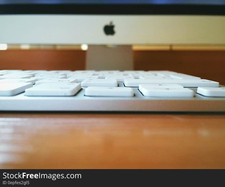 White Computer Keyboard on Brown Wooden Table