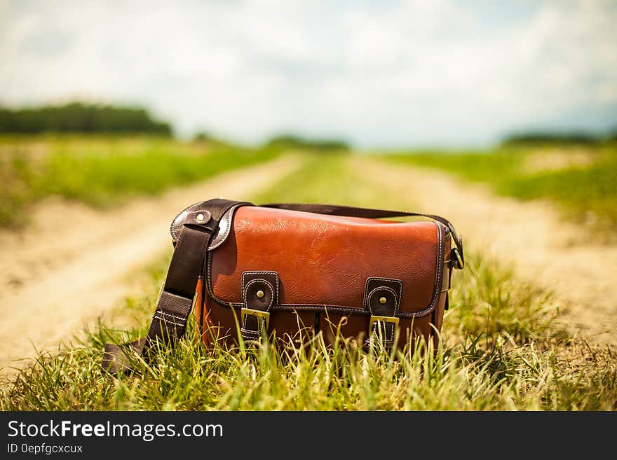 Vintage leather bag on dirt country lane on sunny day. Vintage leather bag on dirt country lane on sunny day.