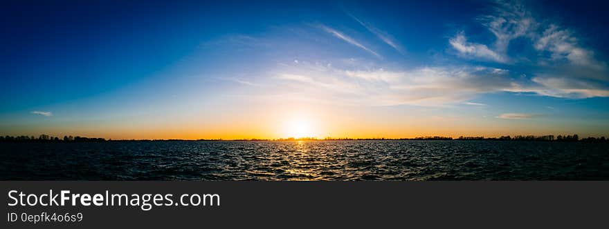 Panoramic horizon of sun set over lake with blue and orange skies. Panoramic horizon of sun set over lake with blue and orange skies.