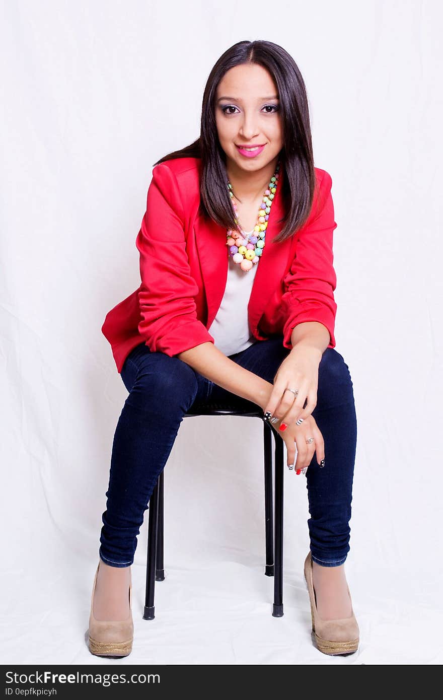 Woman Wearing Red Blazer Sitting on Black Stool