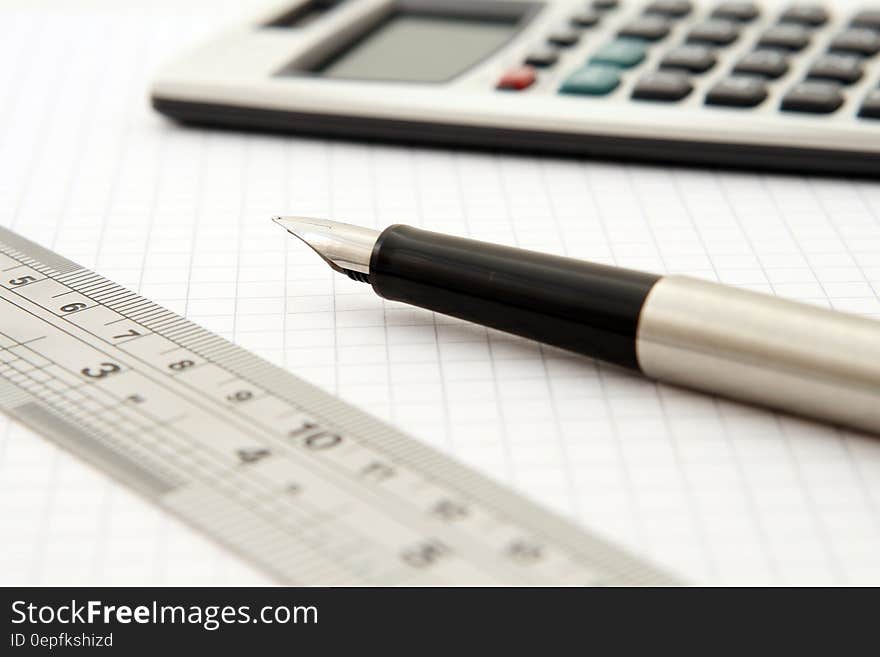 Shallow Focus of Silver and Black Fountain Pen Beside Ruler and Scientific Calculator