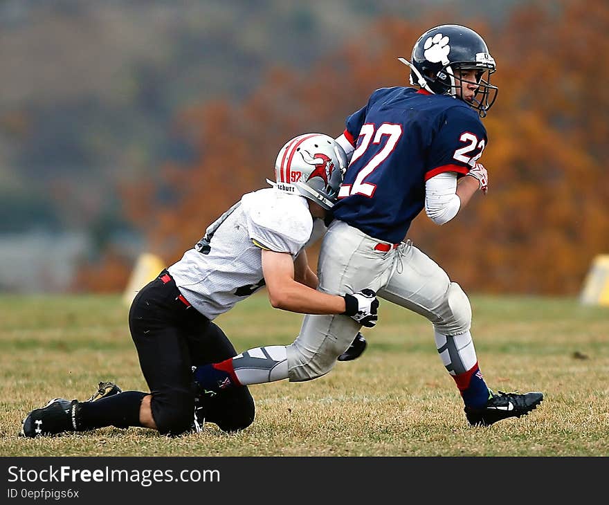 Football Player in White Trying to Stop a Player in Blue