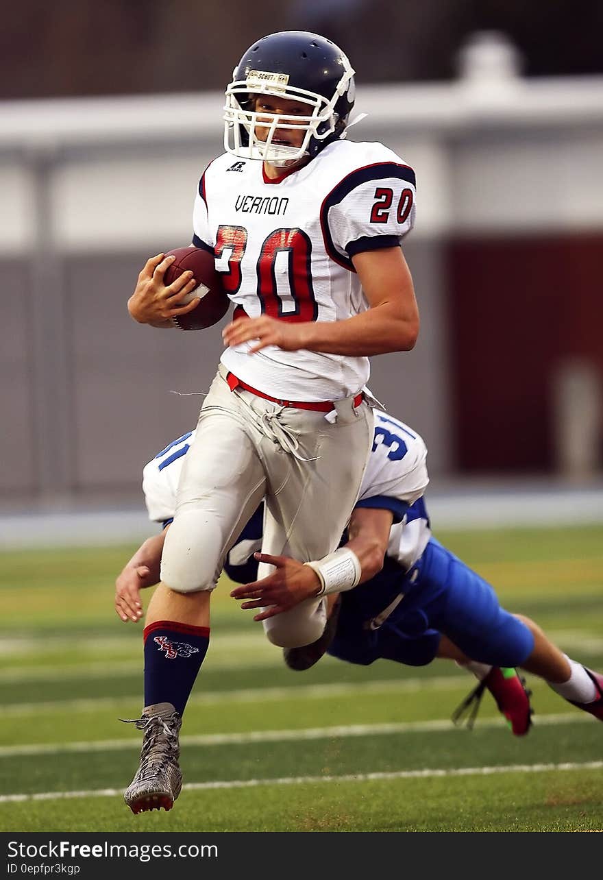 Man Dragging Down the Opponent Holding the Football Running on the Field