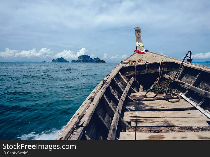 Brown Wooden Boat on Sea Overlooking Rocky Island