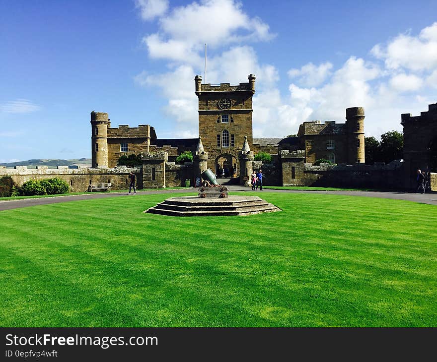 Castle on green lawn against blue skies with white clouds.