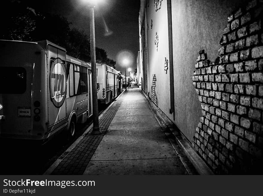 Urban alleyway with trucks parked along sidewalk with streetlamps in black and white. Urban alleyway with trucks parked along sidewalk with streetlamps in black and white.