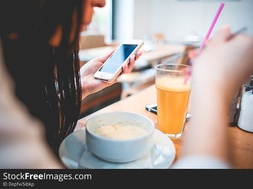 Human Holding Iphone Infront on White Round Bowl