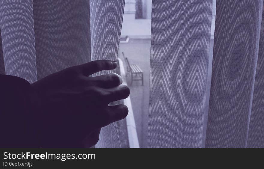 A view of an empty wooden bench through vertical blinds on a window. A view of an empty wooden bench through vertical blinds on a window.