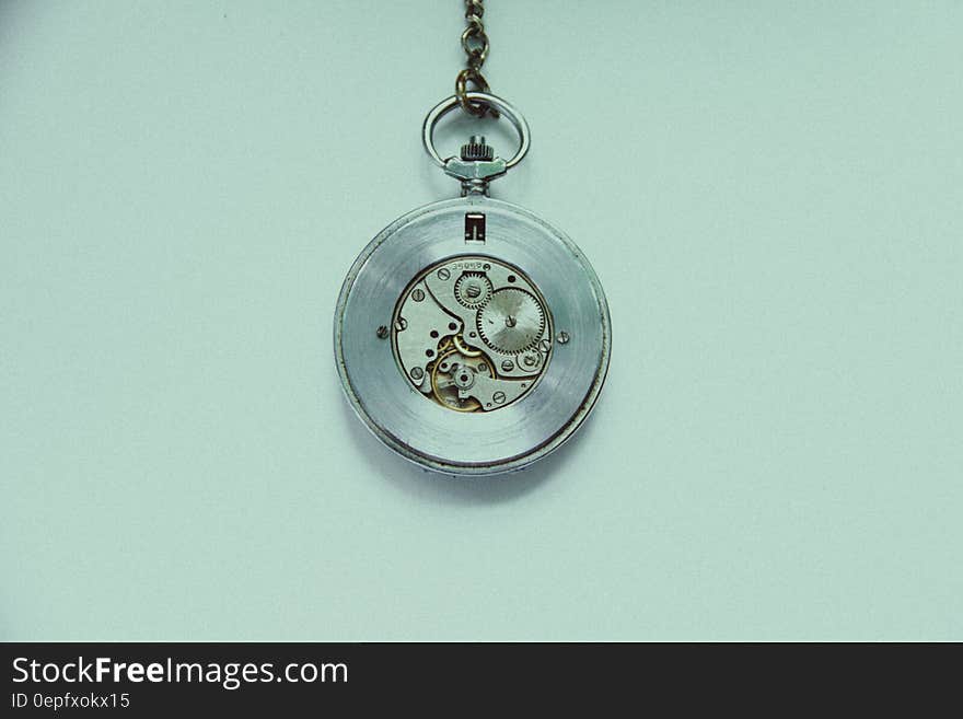 An old fashioned hanging watch on a pale blue background.