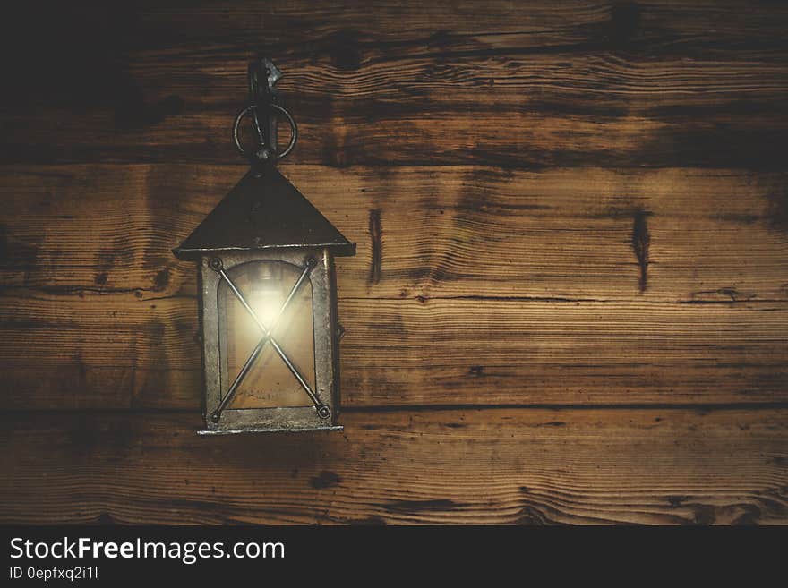 An old fashioned lantern hanging on a wooden wall.