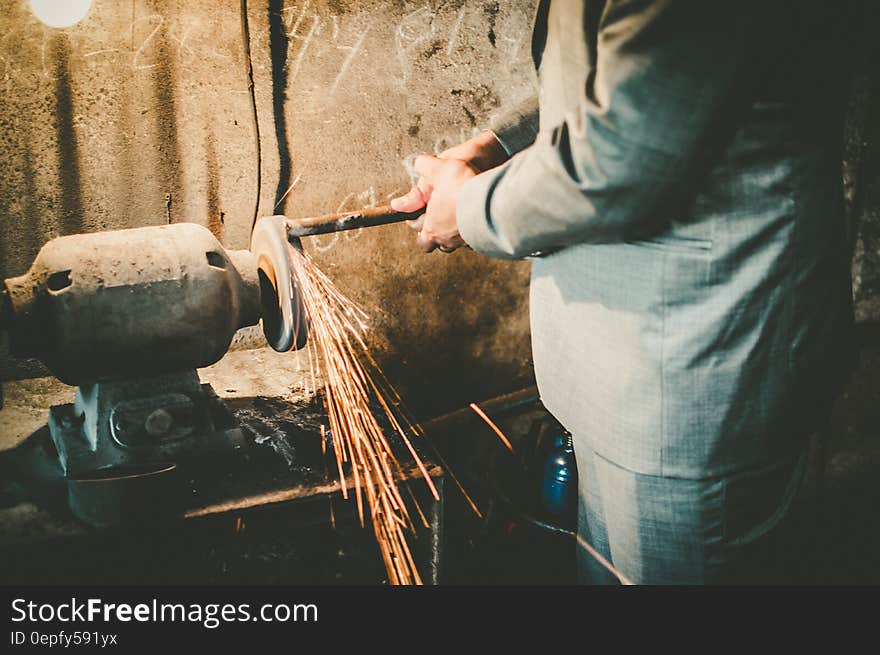 Close up of man in business suit working metal grinder inside factory. Close up of man in business suit working metal grinder inside factory.