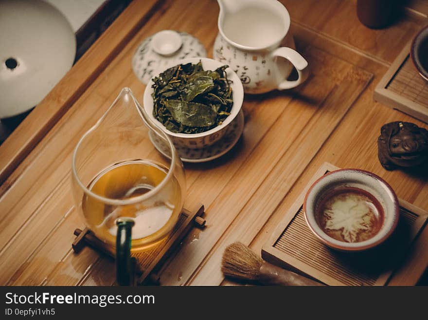 White Ceramic Teapot Beside Cup With Leaves