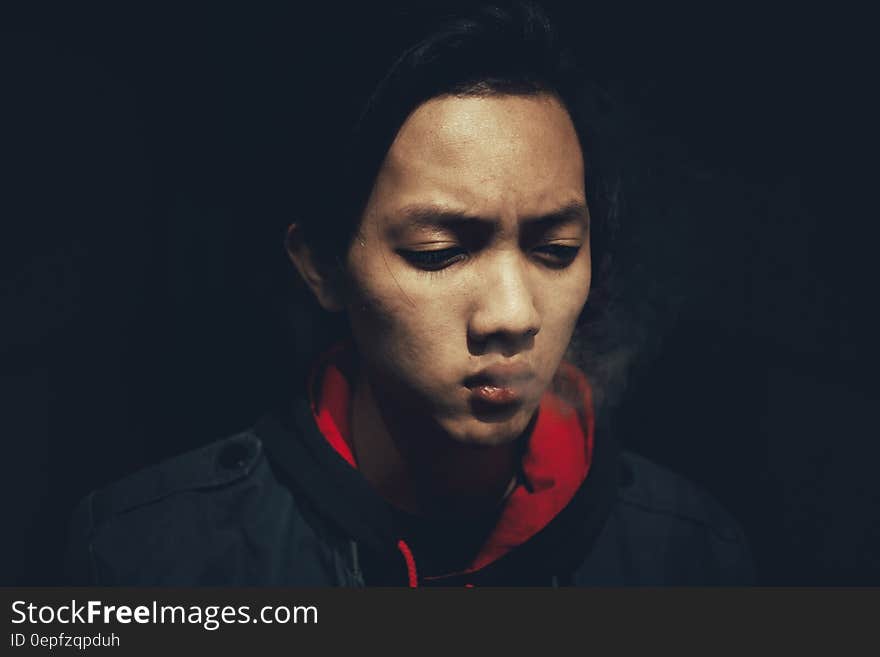 Studio portrait of Asian man in red and black jacket with serious expression. Studio portrait of Asian man in red and black jacket with serious expression.