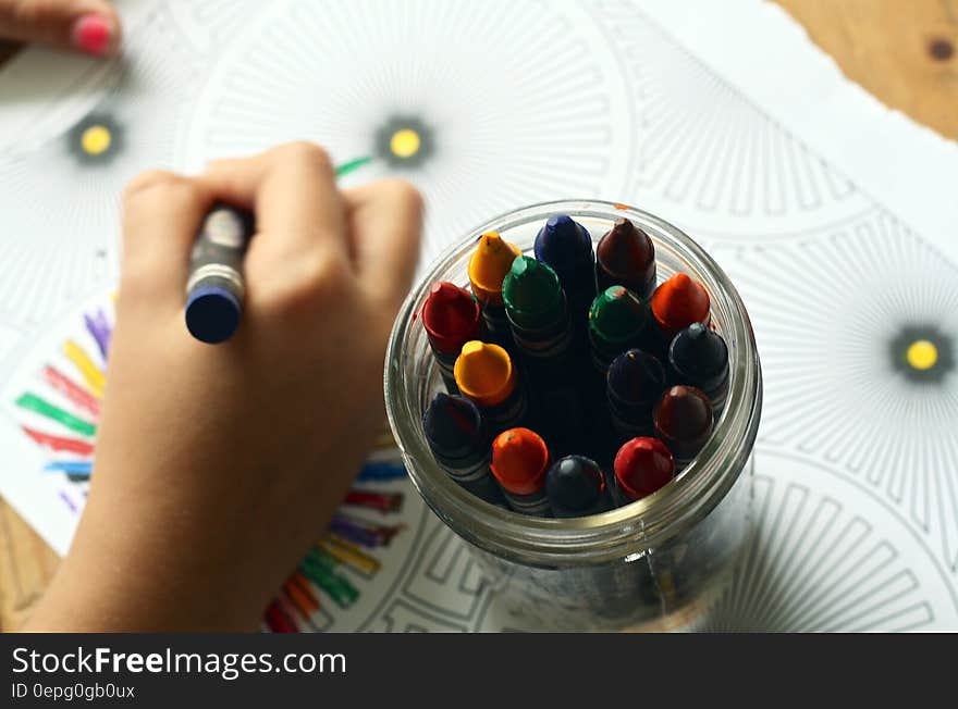 Hand of child using crayons to color printed page. Hand of child using crayons to color printed page.