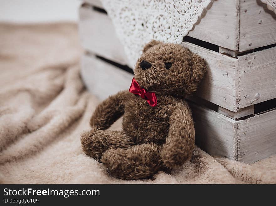 A teddy bear leaning on a wooden crate.