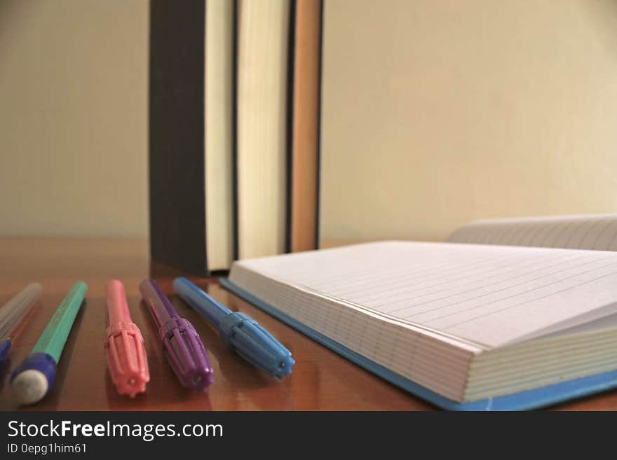 Colorful pencils and markers next to an open notebook. Colorful pencils and markers next to an open notebook.