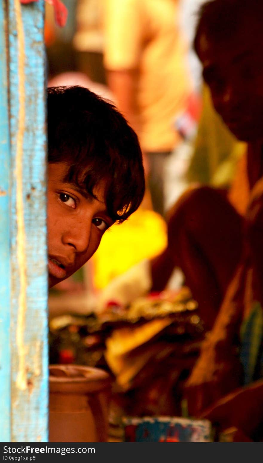 A boy peeking from behind a door frame. A boy peeking from behind a door frame.