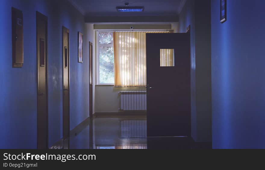 A dark hallway of a hospital or sanitarium with one door open.