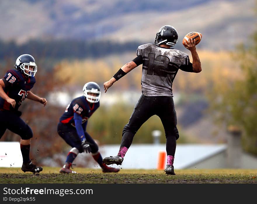 2 Football Player Running After Person Holding Football during Daytime in Shallow Focus Photography