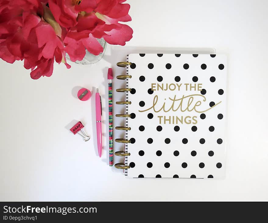 A polka dot notebook with writing supplies and a flower bouquet.