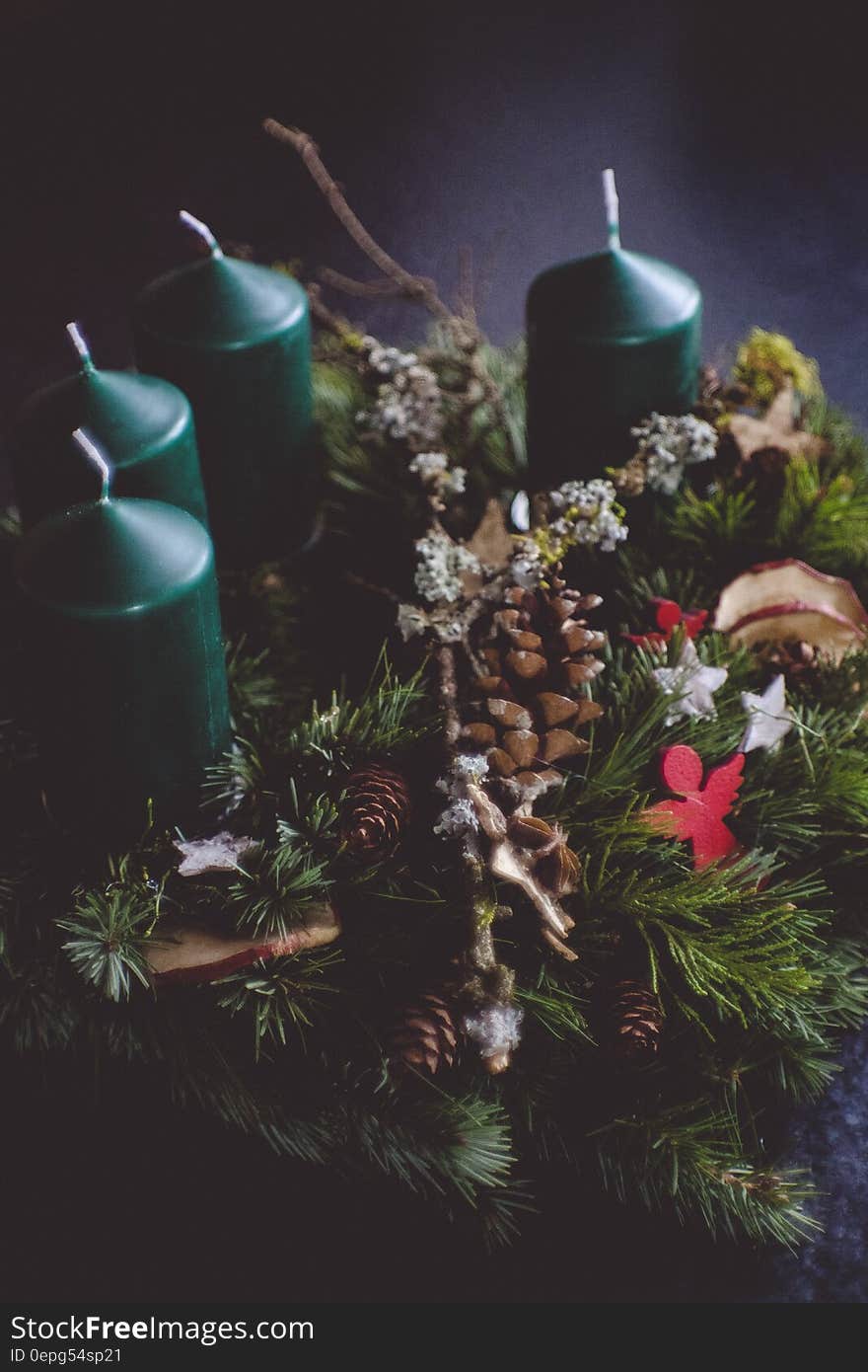 A Christmas wreath with conifer branches and cones and candles in the background. A Christmas wreath with conifer branches and cones and candles in the background.