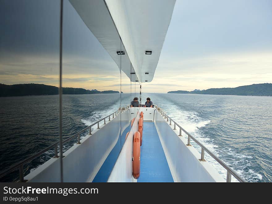 Two people sitting on a sailboat deck. Two people sitting on a sailboat deck.