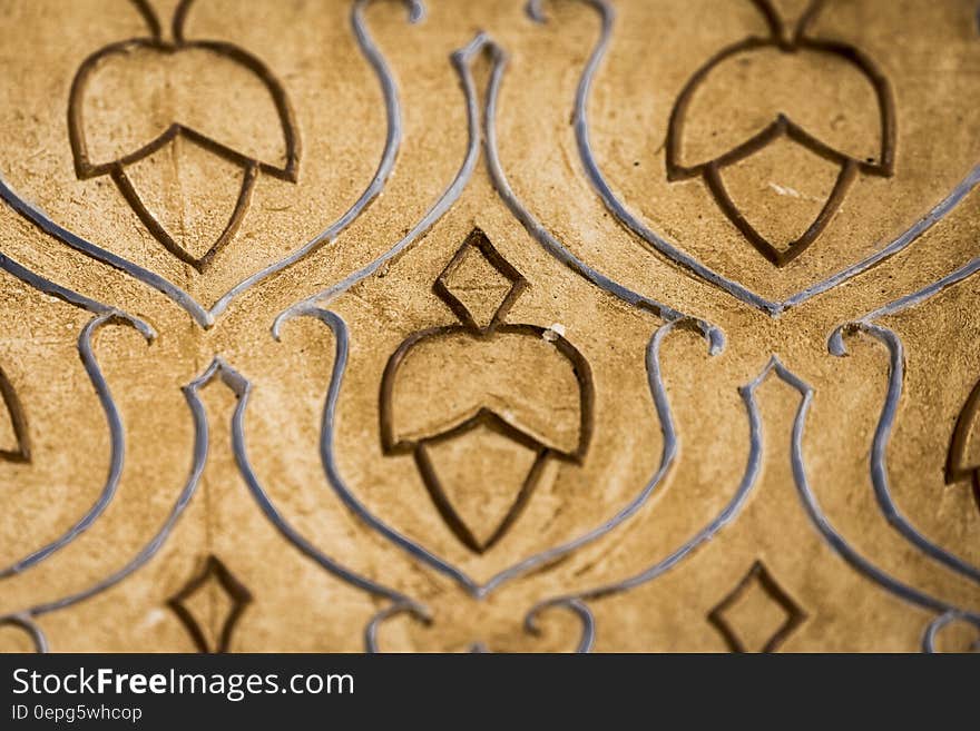 Abstract pattern of an acorn shape repeated and engraved into the surface of beige tile. Additional swirls around the acorns frame and emphasize the subject. Abstract pattern of an acorn shape repeated and engraved into the surface of beige tile. Additional swirls around the acorns frame and emphasize the subject.