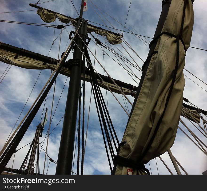 Sails folded on masts on sailboat against blue skies on sunny day. Sails folded on masts on sailboat against blue skies on sunny day.