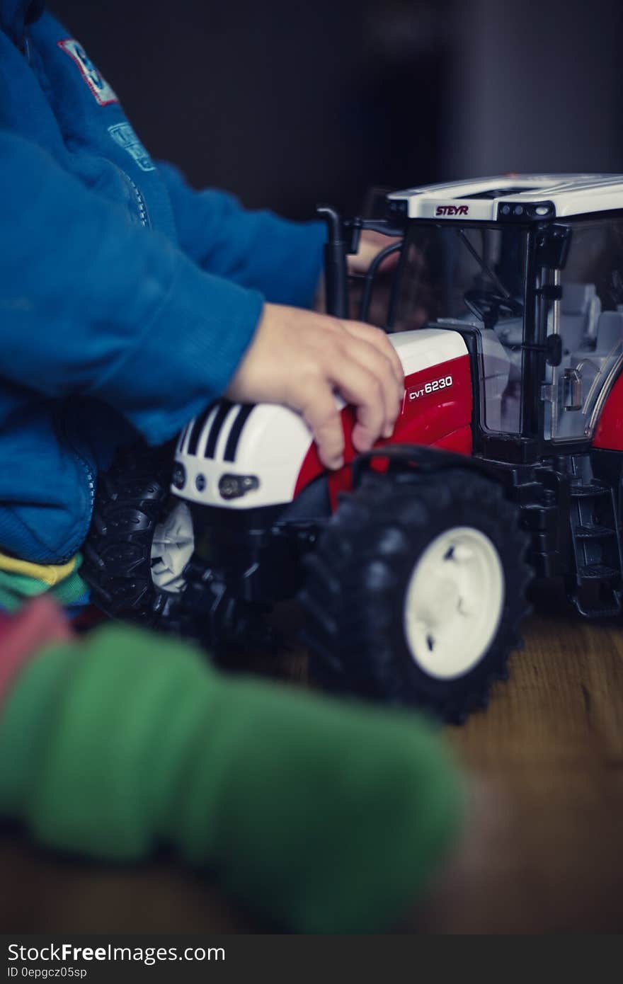 Close up of child playing on floor with toy tractor. Close up of child playing on floor with toy tractor.