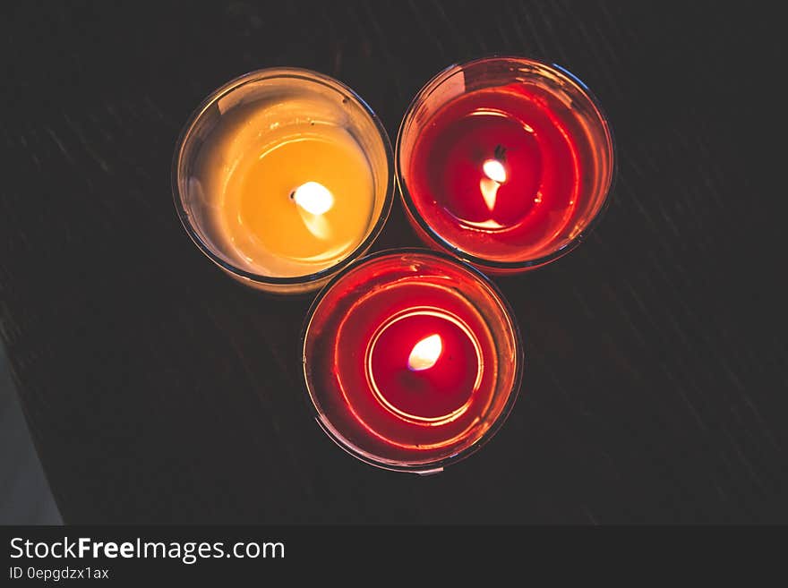 Lighted Red Wax Candle on Clear Drinking Glass