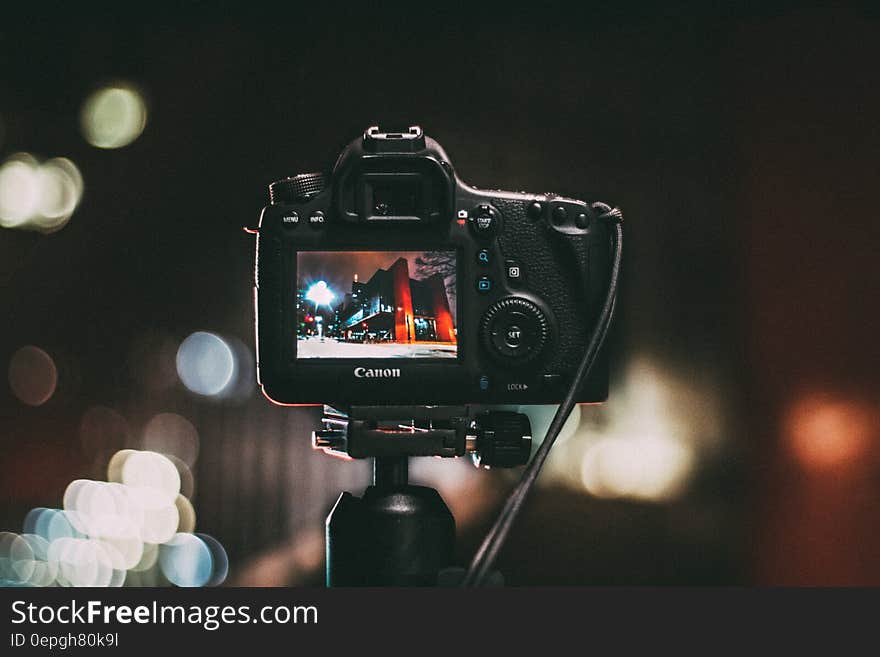 Rear view of digital Canon camera on monopod taking picture of city night scene. Rear view of digital Canon camera on monopod taking picture of city night scene.